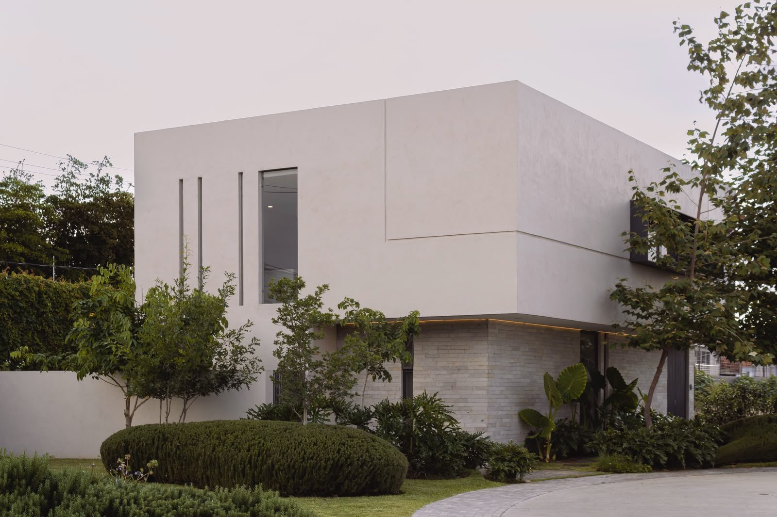 Residencia Monolito, fachada minimalista con piedra y jardín
